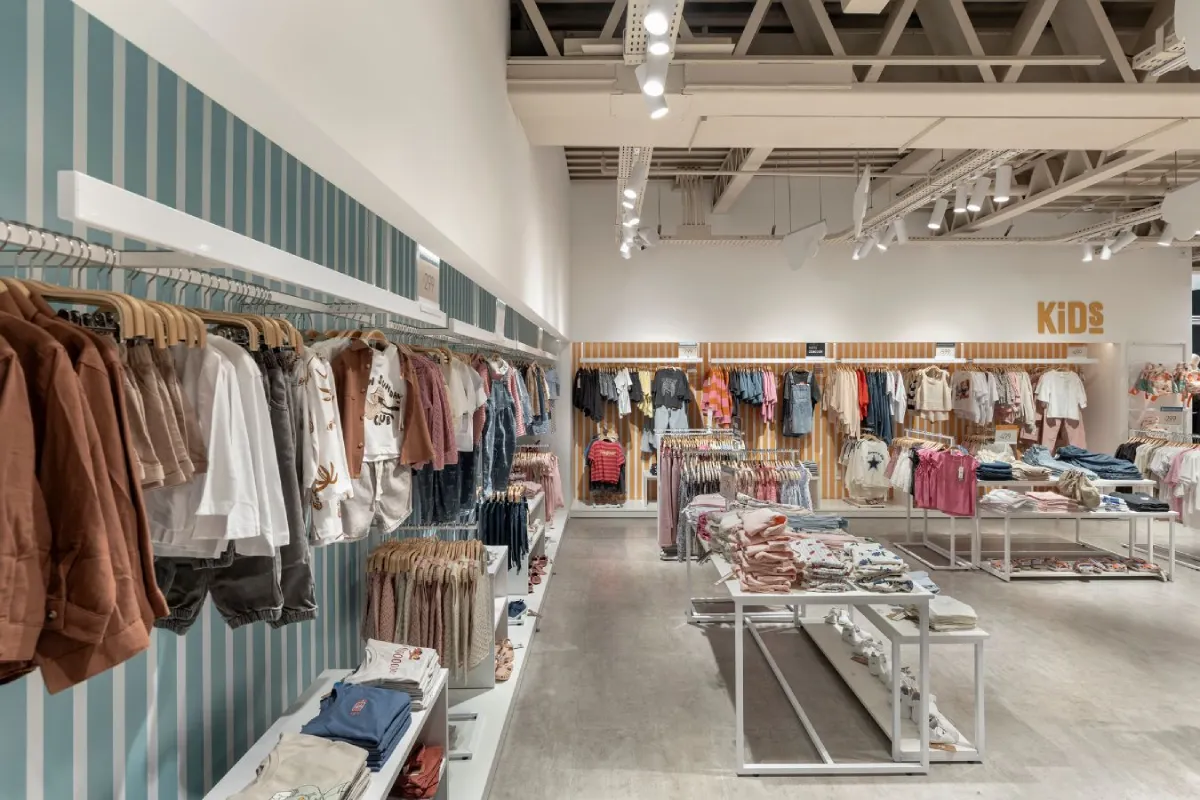 BAS Retail Store - Wall-mounted clothing displays with industrial track lighting above - Contract Workplaces.webp